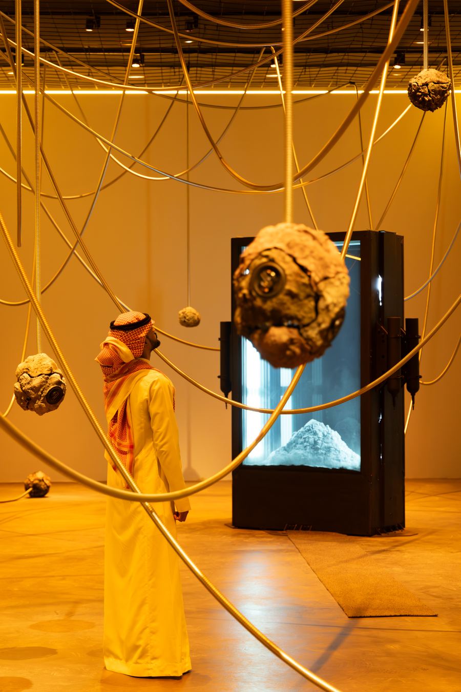 Visitor beneath suspended clay spheres, JAX District